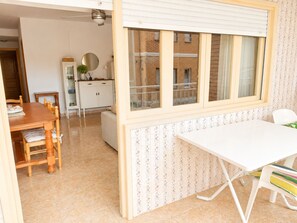 Una habitación con una mesa de comedor, sillas, un escritorio blanco y una ventana con persianas.