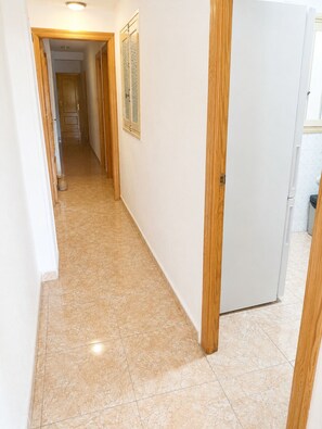 A hallway with a tiled floor, wooden doors, and a white wall. - Beachfront Apartment in Los Alcázares - Murcia (Los Alcázares)