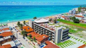 Et kysthotel med flere etager, en swimmingpool og udsigt til stranden.