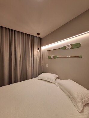 A bedroom with a bed, curtains, two wall-mounted paddleboards, and a pendant light. - Studio beira-mar nas piscinas naturais Tamandaré (Tamandaré)