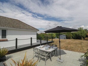 Eine Terrasse mit Essbereich, umgeben von einem weißen Zaun und einem Garten.