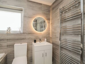 Een moderne badkamer met toilet, wastafel en een douchecabine met glazen wanden.