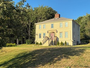 Une maison à deux étages avec un porche à l’avant et une cheminée.