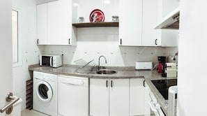 A compact kitchen with a washing machine, microwave, toaster, and a coffee maker. - Stylish 2-bedroom Andalusian apartment in the historic center, with Wi-Fi and central air conditioning (Sevilla)