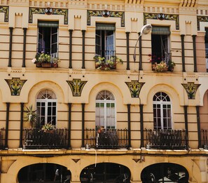 A building with multiple windows, balconies with potted plants, and decorative architectural elements. - Vrbo Property (Sevilla)