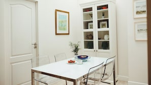 Un coin repas avec une table blanche, des chaises et un buffet aux portes vitrées.