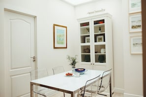 A dining area with a white table, chairs, and a cabinet with glass doors. - Vrbo Property (Sevilla)