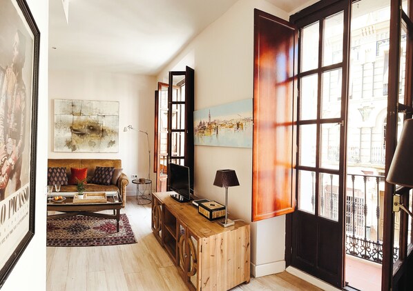 A living room with a sofa, TV, and artwork. - Vrbo Property (Sevilla)