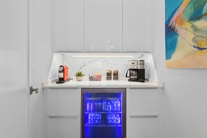 A kitchenette with a coffee machine, a small potted plant, and a beverage dispenser. - Modern 3BR • Private Backyard • Minutes to Downtown & Siesta Key (Sarasota)