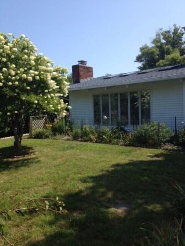 A single-story house with a sloped roof, a chimney, and a front porch with a railing.