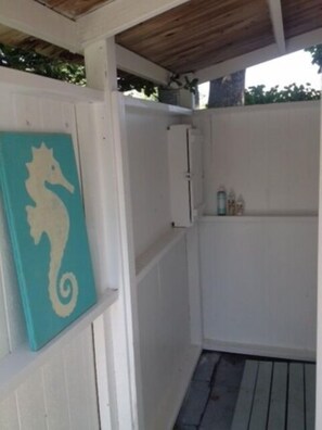 A small, enclosed outdoor area with a wooden ceiling, a white cabinet, and a teal seahorse painting on the wall. - fully renovated leisurama near private beach (Montauk)