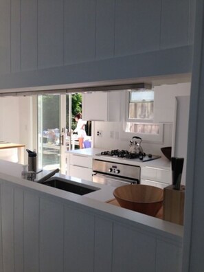 A modern kitchen with white cabinetry, a gas stove, and a large window.