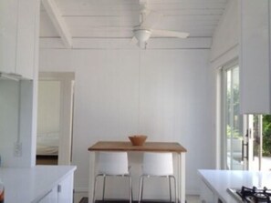 A room with a ceiling fan, a table with two chairs, and a window.