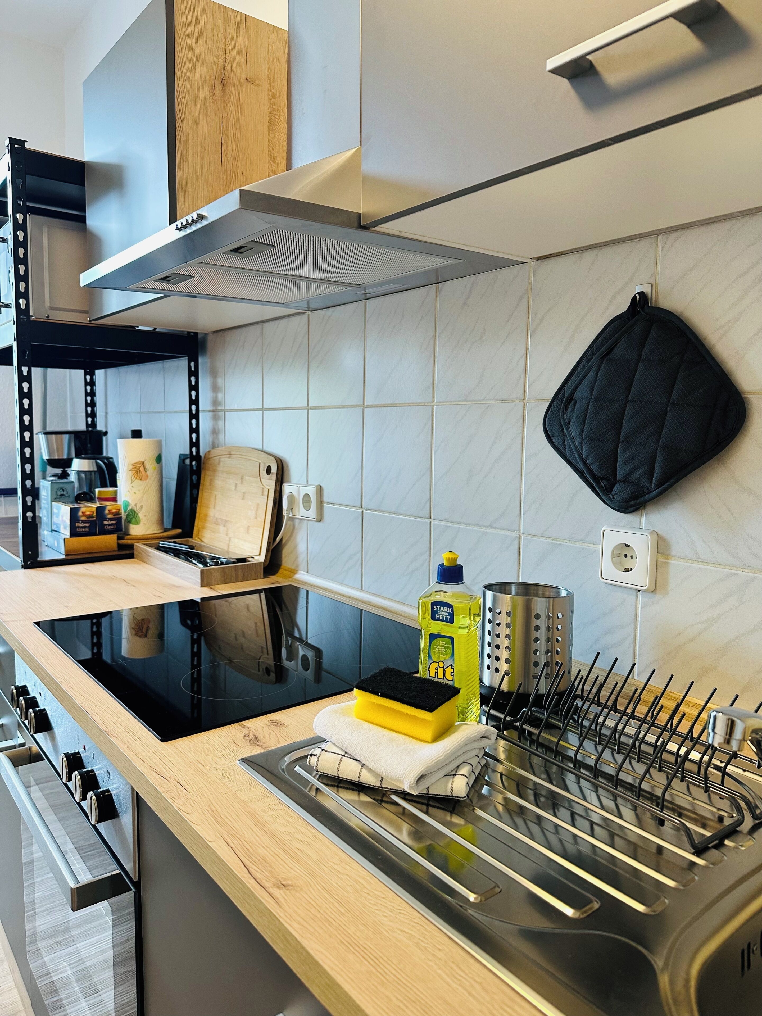 Une cuisine moderne avec un poêle noir, un plan de travail en bois et un évier en acier inoxydable.