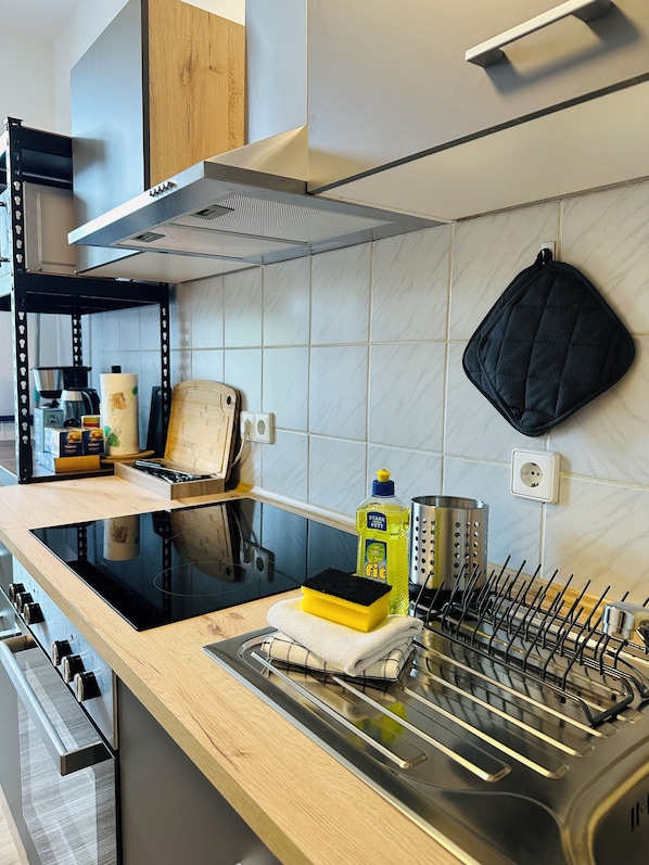 A modern kitchen with a black stove, wooden countertop, and a stainless steel sink.