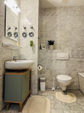 A bathroom with a sink, toilet, mirror, and marble tiles. - Stylish 2BR apartment (Leipzig)