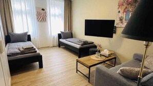 Ett modernt vardagsrum med en soffa, en mindre divansoffa, ett soffbord och en platt-TV som är monterad på väggen.