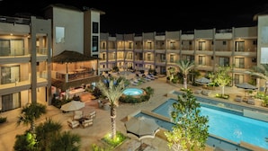A hotel with a pool, lounge areas, and a courtyard with palm trees. - Brand New Luxury Condo Near Eagle Beach-Pool & Gym, Walishali Condos (Oranjestad)