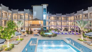A hotel with multiple swimming pools, outdoor seating areas, and a central bar/lounge area. - Brand New Luxury Condo Near Eagle Beach-Pool & Gym, Walishali Condos (Oranjestad)