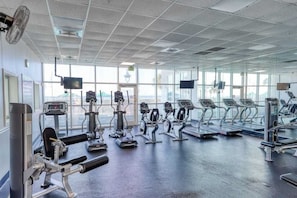 Ein Fitnessstudio mit Cardiogeräten, Krafttrainingsgeräten und großen Fenstern.