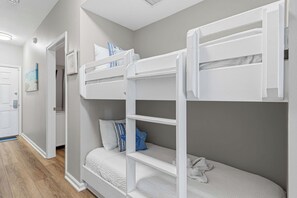 Ein Zimmer mit Etagenbetten, einer Tür, einem gerahmten Bild und einem Lichtschalter.