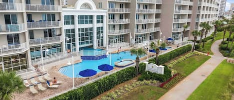 Un hôtel à plusieurs étages doté d’une piscine centrale, d’un espace extérieur aménagé et d’un jardin bien entretenu.