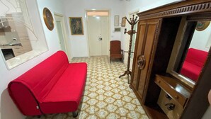 Quarto com sofá vermelho, armário de madeira e piso estampado.