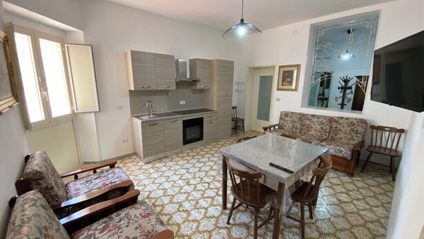 Um espaço de estar compacto com cozinha americana, área de jantar com mesa e cadeiras, e um sofá.