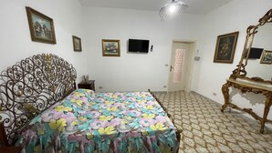 Quarto com cama, televisão, porta e espelho.
