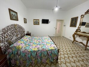 Ein Schlafzimmer mit einem Bett, einem Fernseher, einer Tür und einem Spiegel.