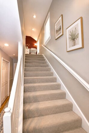 A carpeted staircase with white handrails, leading to a room with a window and a door. - Near downtown, Tremont, Ohio City, Rock Hall (Cleveland)