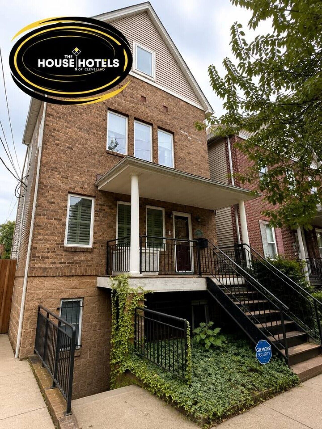 A two-story brick building with a balcony and a staircase leading to the entrance.