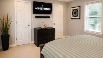 A bedroom with a bed, a ceiling fan, a TV, and a dresser.