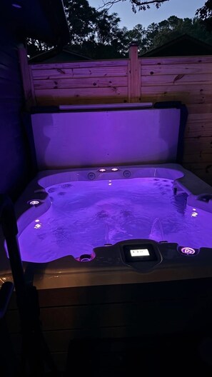 Ein Whirlpool mit Holzterrasse und Holzzaun im Hintergrund.