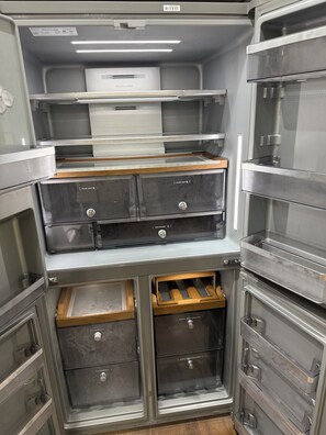 Una cocina con electrodomésticos de acero inoxidable, encimeras de madera y varios cajones de almacenamiento.