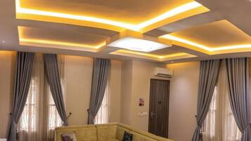 Habitación con sofá, cortinas e iluminación empotrada en el techo.