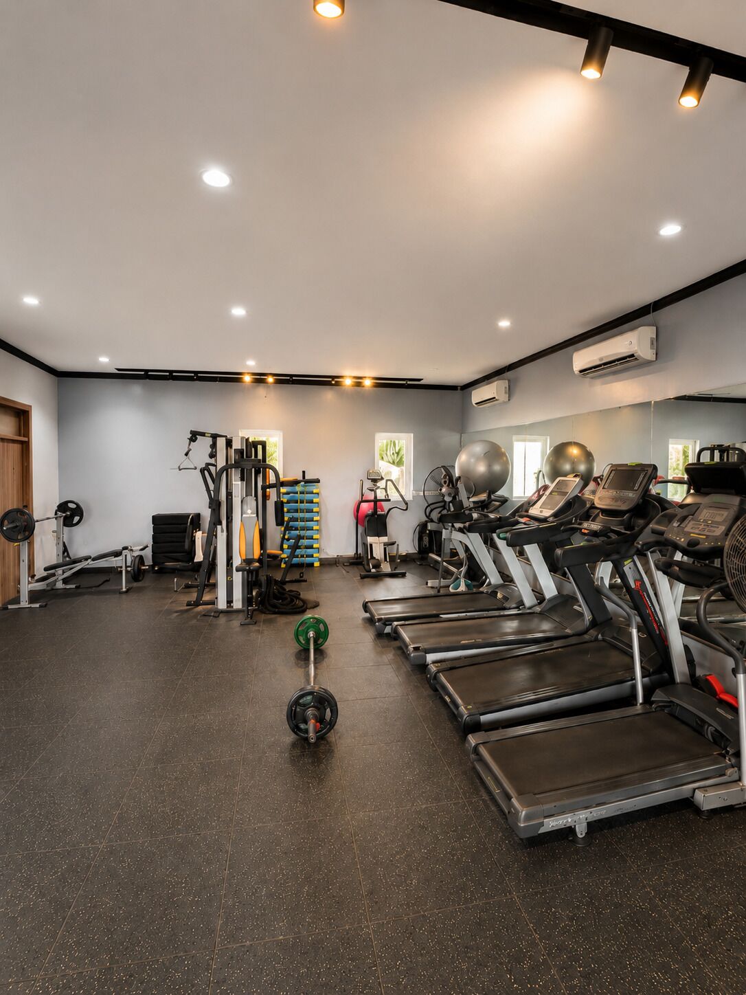 Ett gym med löpband, styrketräningsmaskiner och en vägg täckt med speglar.
