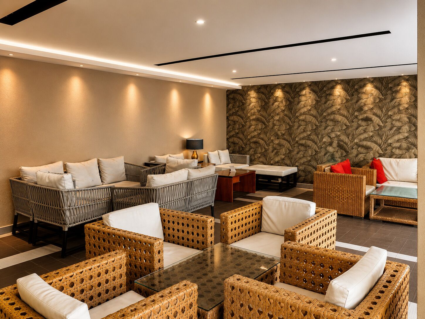A modern lounge area with wicker furniture, a glass-top table, and a patterned wall.