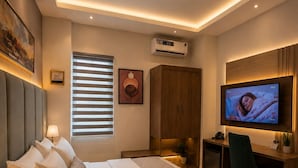 A modern hotel room with a large bed, a desk, a television, and an air conditioning unit. - Kiniz Apartments and Hotel Uyo (Uyo)