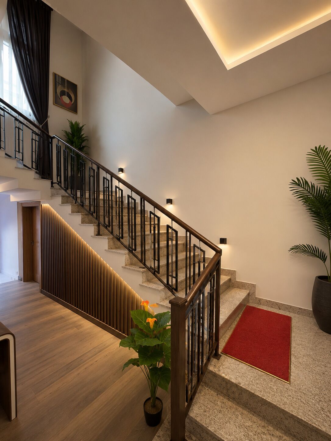 Un escalier moderne avec une rampe en bois, une moquette rouge au bas et une plante en pot sur la plateforme.