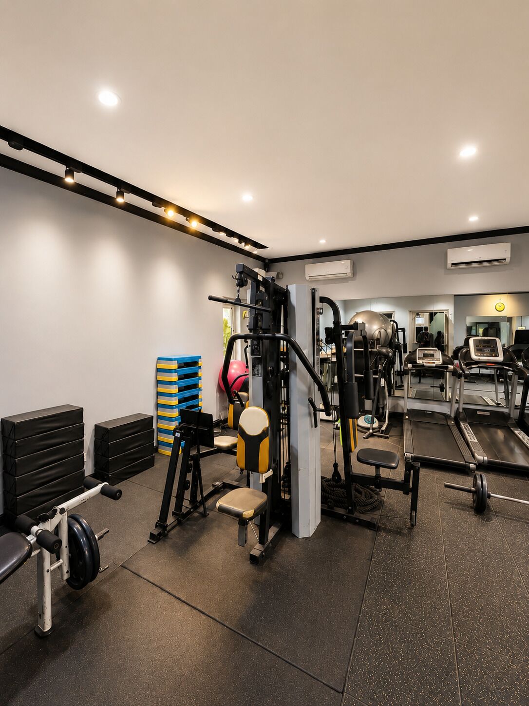 Une salle de sport équip ée de divers appareils d’exercice, notamment un tapis de course, des appareils de musculation et un banc.