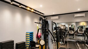 A gym with various exercise equipment, including a treadmill, weight machines, and a bench.