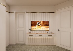 Ein Zimmer mit Fernseher an der Wand, einer Tür und einem kleinen Schrank mit Schubladen.