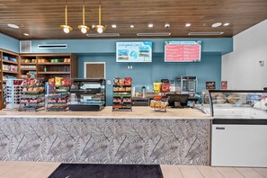 A snack bar with shelves stocked with chips and snacks, a refrigerated display case, and a menu board advertising a 'Breeze Canteen' and 'Volleyball Court'. - 7BR house with private pool in clermont (Clermont)