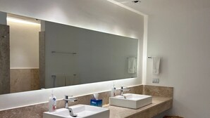 A bathroom with two sinks, a large mirror, and a waste basket. - 2BR Apartment with Beach Club (Cancún)