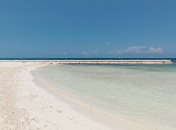 Une plage avec une eau claire et peu profonde et un rivage sablonneux.