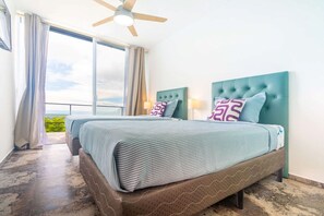 A bedroom with a large bed, a ceiling fan, and a view of the outdoors. - Your tropical retreat overlooking Corcovado, featuring a private pool and lush natural surroundings. (Puerto Cortes)