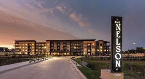 Ein mehrstöckiges Hotelgebäude mit einer auffälligen vertikalen Schrifttafel, die den Namen 'The Nelson' zeigt.