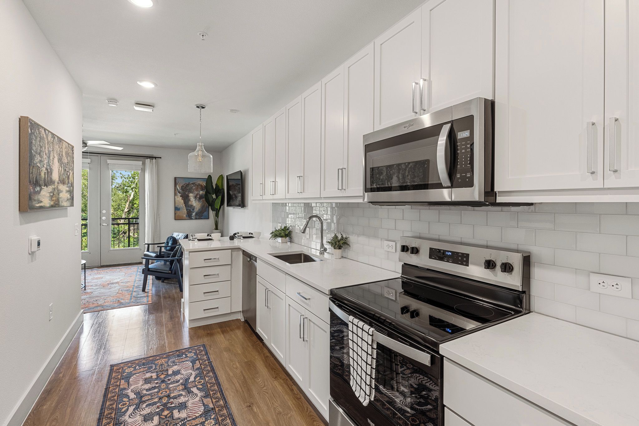 A modern kitchen with white cabinetry, stainless steel appliances, and a black oven.
