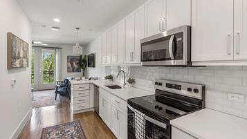 A modern kitchen with white cabinetry, stainless steel appliances, and a black oven.